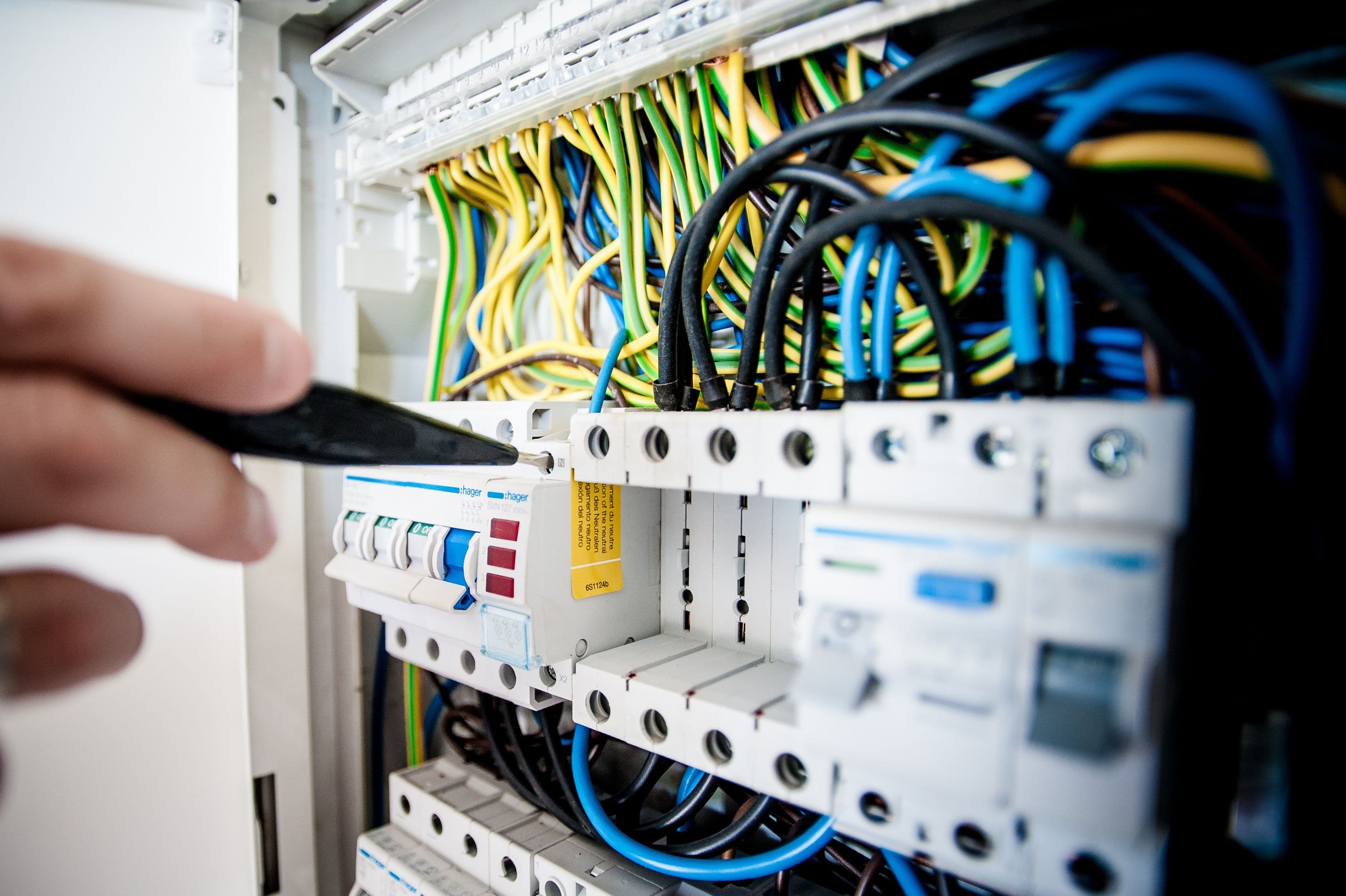 Mãos de técnico a trabalhar num quadro elétrico aberto